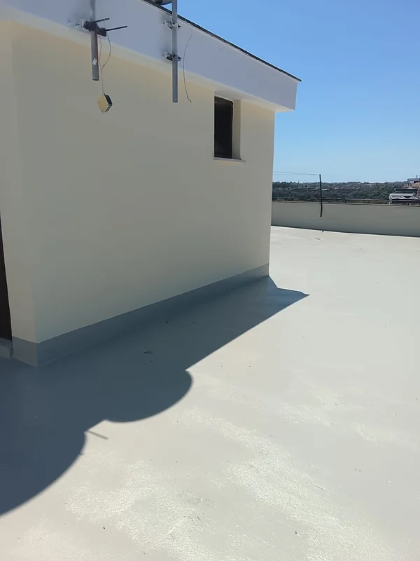 Superficie chiara della copertura e raccordo alla base del locale tecnico, con zone al sole e in ombra.