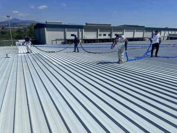 Squadra con attrezzatura e tubazioni su ampia copertura industriale in lamiera grecata.