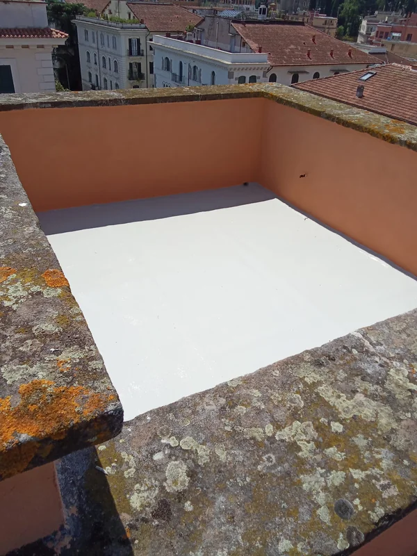 Vista dall’alto di una porzione di copertura con rivestimento chiaro e raccordi alle pareti perimetrali.