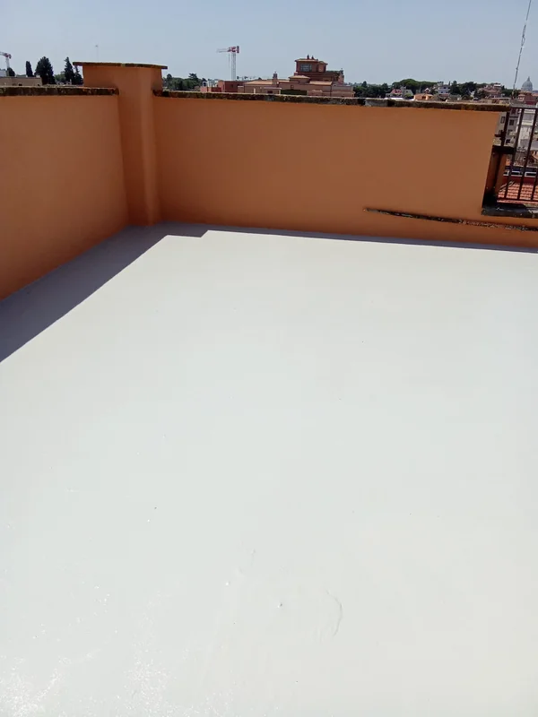 Copertura piana con rivestimento chiaro, risvolti perimetrali e parapetti color arancio.