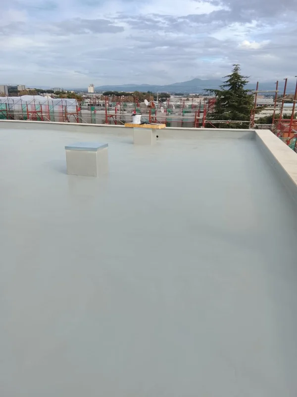 Copertura con rivestimento chiaro, elementi emergenti e ponteggi lungo il perimetro.