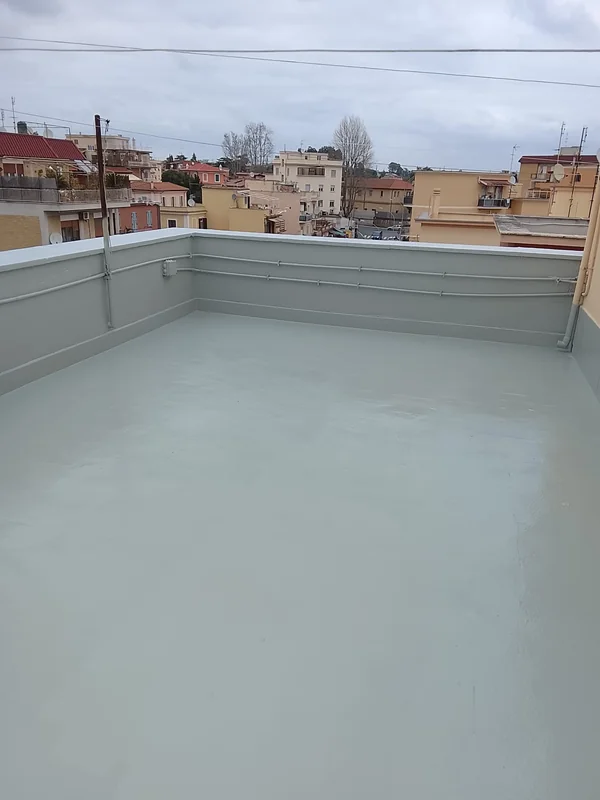 Copertura piana con rivestimento grigio uniforme e risvolti lungo i parapetti e le tubazioni.