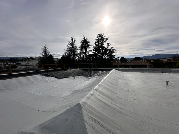 Copertura con superfici inclinate, raccordi e rivestimento chiaro durante una fase di lavoro.
