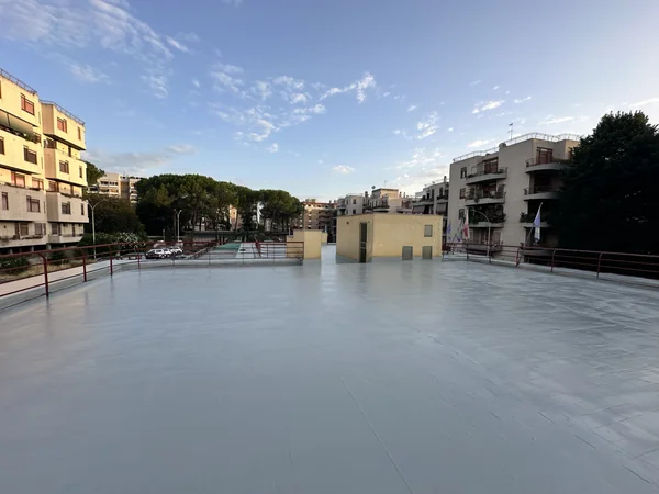 Vista della copertura con rivestimento grigio e locali tecnici sullo sfondo.