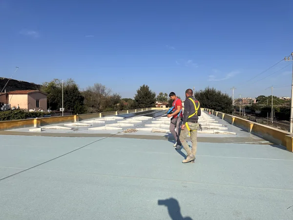 Operatori sulla copertura con pannelli isolanti, giunti e porzioni di superficie rivestite.