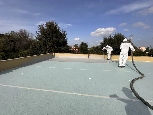 Una fase di applicazione a spruzzo del rivestimento della copertura vicino ai parapetti.