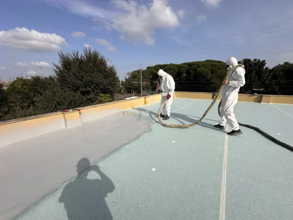 Operatori e tubazioni durante la lavorazione del rivestimento su copertura piana.
