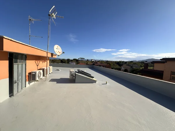 Copertura piana con rivestimento grigio e raccordi lungo i parapetti e gli elementi emergenti.