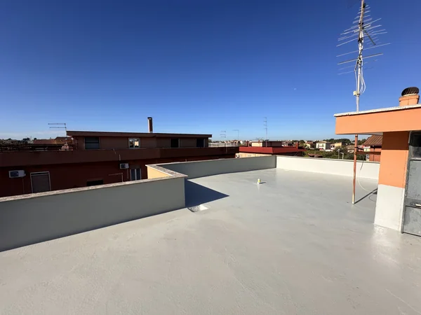 Copertura rivestita con parapetti, locale tecnico e antenna sullo sfondo.